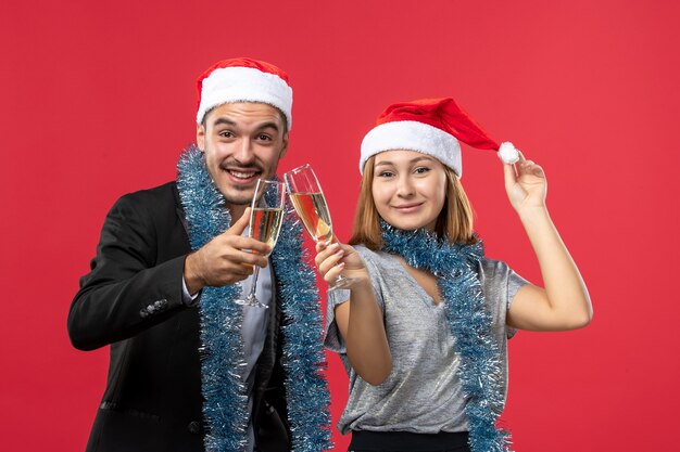 Front view young couple celebrating new year on the red wall love christmas party drink