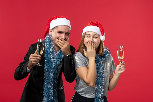 Front view young couple celebrating new year on the red wall love christmas party drink