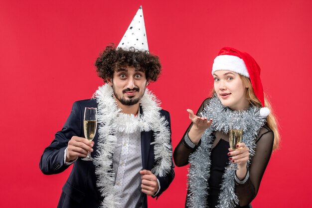 Giovani coppie di vista frontale che celebrano il nuovo anno sulla festa di natale di amore della parete rossa