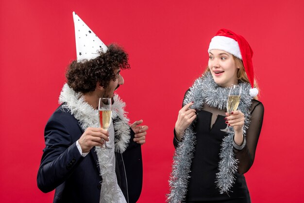 Front view young couple celebrating new year on red wall party holiday christmas love