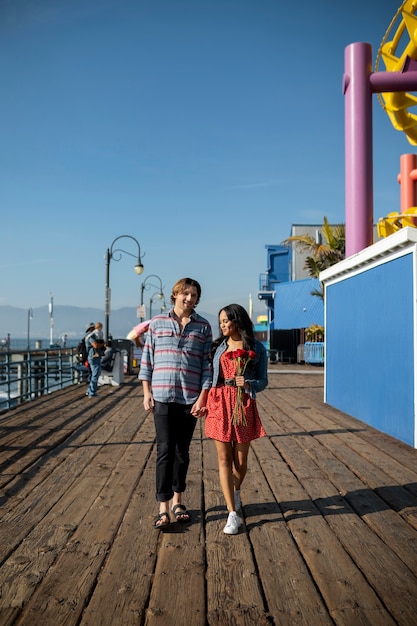 Front view of young couple on a date walking while holding hands at the amusement park