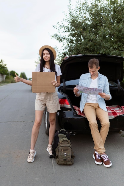 Front view young couple hitch hiking on holiday