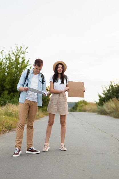 Front view young couple hitch hiking