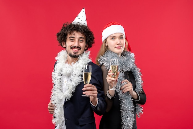 赤い壁のクリスマスの愛のパーティーの色でちょうど新年を祝う正面図の若いカップル