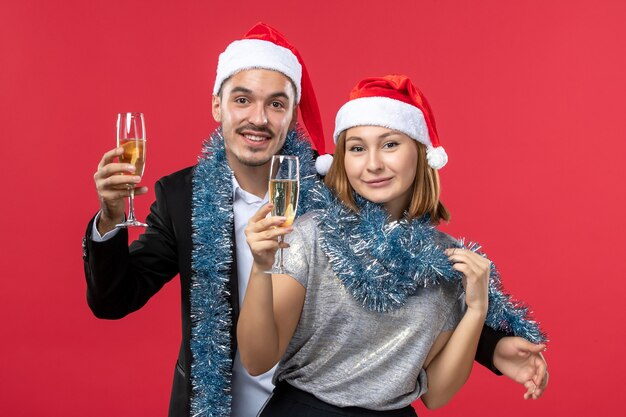 Front view young couple just celebrating new year on a red wall party love christmas
