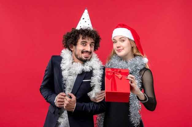 Front view young couple with new year present on red desk christmas love holiday