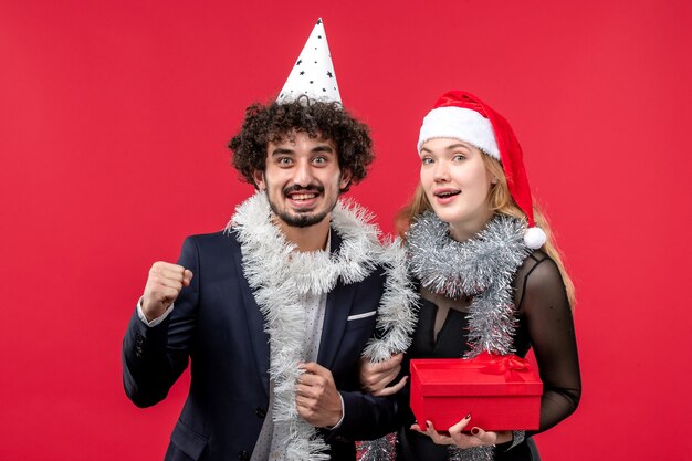 赤い机のクリスマスの愛のパーティーに新年のプレゼントと正面図の若いカップル
