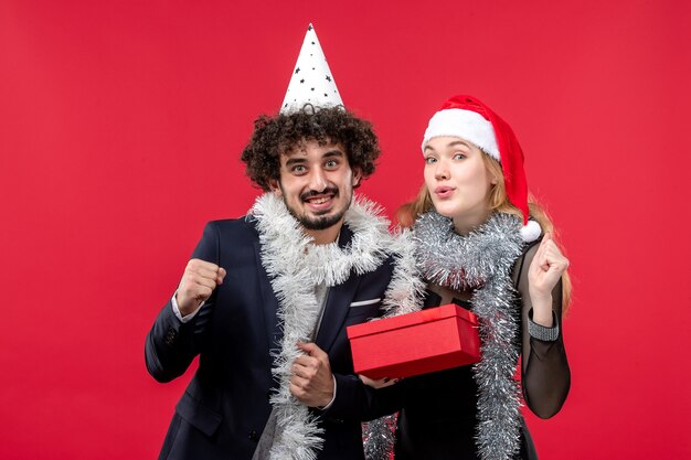 Front view young couple with new year present on red floor christmas love party