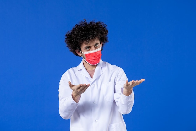 파란색 배경 약물 covid-대유행 의학 바이러스 백신 건강에 빨간 마스크를 쓴 의료복을 입은 젊은 의사
