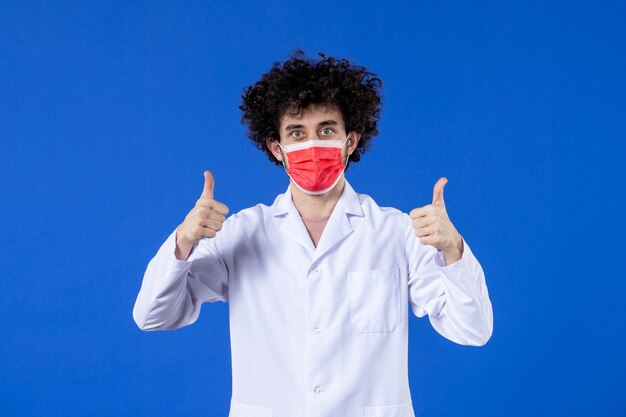 파란색 배경 바이러스 약물 코비드-대유행 병원 백신 건강에 빨간 마스크를 쓴 의료복을 입은 젊은 의사