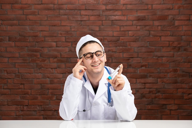 Front view young doctor in white medical suit holding little flask