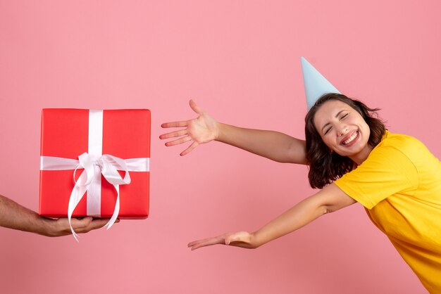 ピンクの床に男性からのプレゼントを受け入れる正面図若い女性新年の感情クリスマスパーティー女性の色