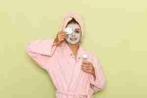 Free photo front view young female after shower in pink bathrobe removing her mask on a green surface