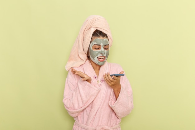 Front view young female after shower in pink bathrobe talking on the phone on a green surface