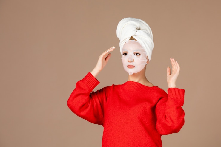 Free Photo front view of young female applying face mask on brown wall
