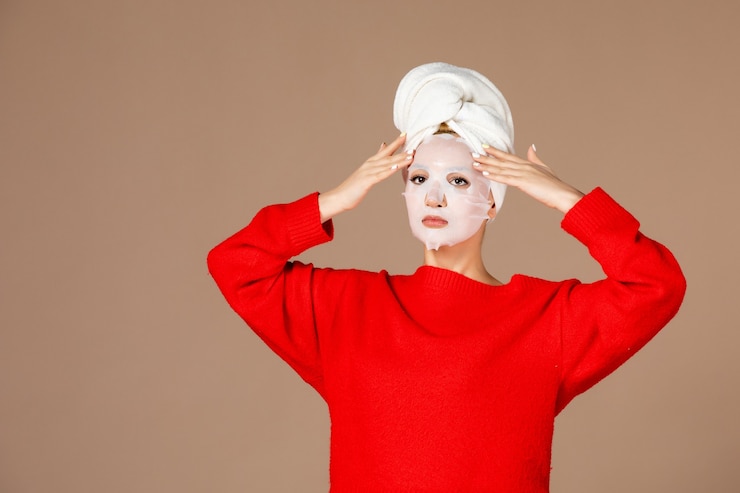 Free Photo front view of young female applying face mask on brown wall
