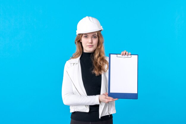 Front view young female architect in helmet on blue