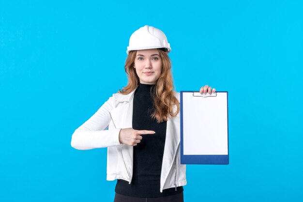 Front view young female architect in helmet on blue