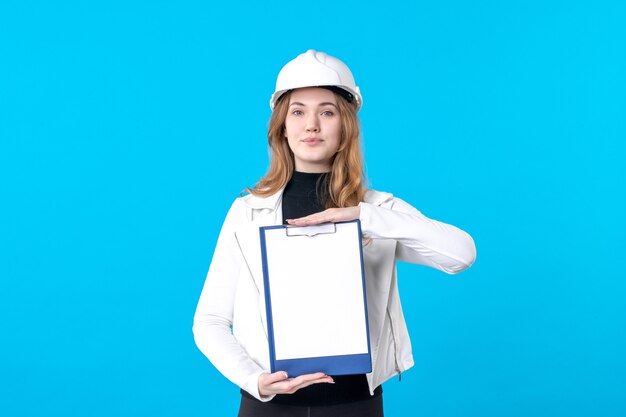 Front view young female architect holding file note on blue