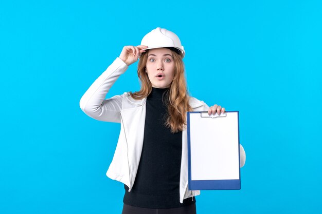 Front view young female architect holding file note on blue