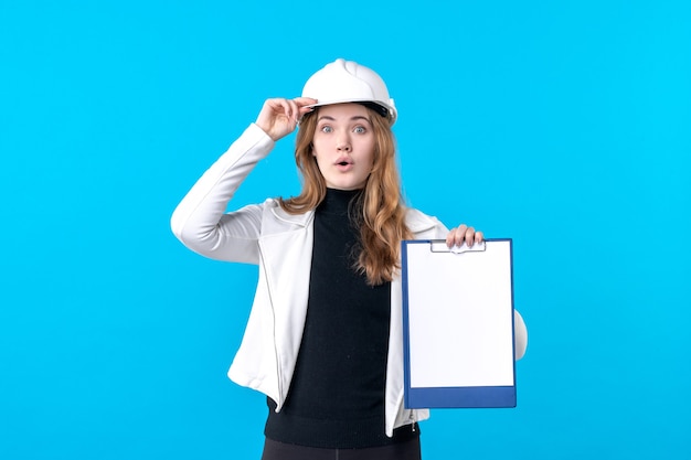 Вид спереди молодой женщины-архитектора, держащей файл заметки на синем
