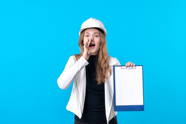 Front view young female architect holding file note on blue