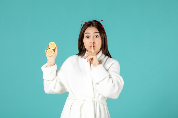 front view young female in bathrobe holding sliced lemons on blue background