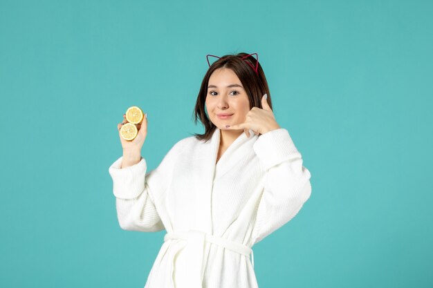 front view young female in bathrobe holding sliced lemons on blue background