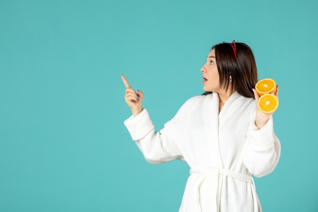 front view young female in bathrobe holding sliced orange on blue background