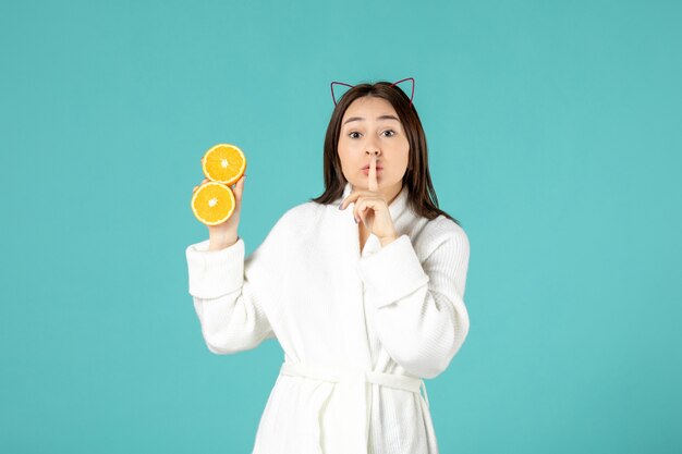 front view young female in bathrobe holding sliced orange on blue background