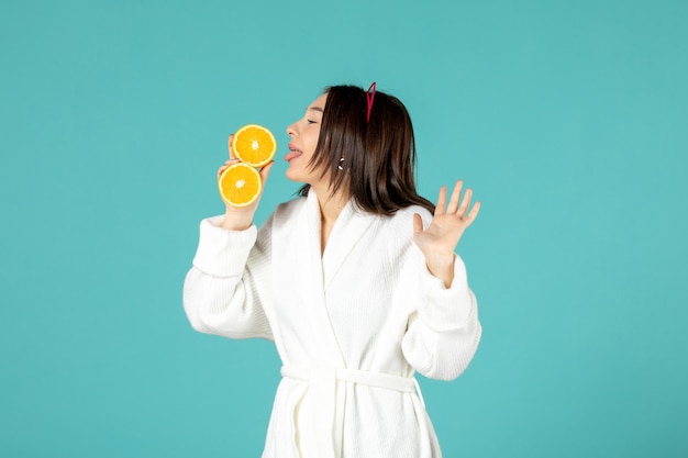 front view young female in bathrobe holding sliced orange on blue background