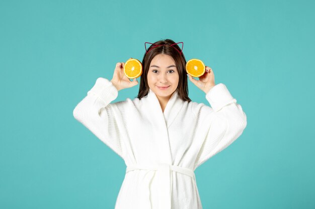 front view young female in bathrobe holding sliced orange on blue background