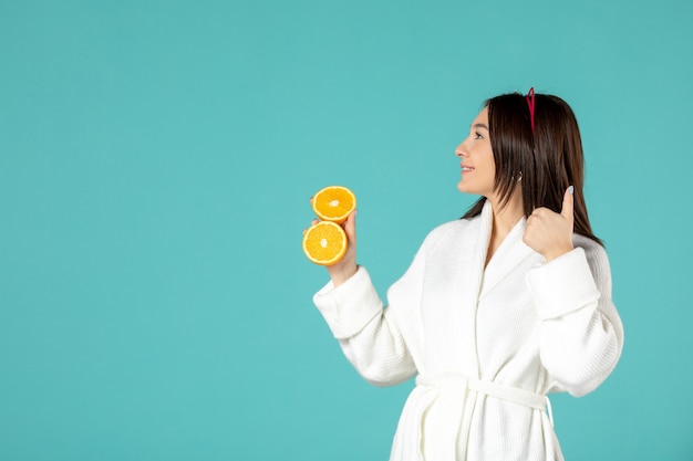 front view young female in bathrobe holding sliced orange on blue background