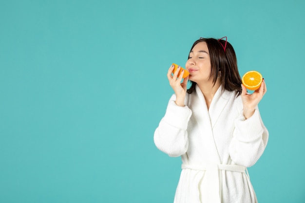 front view young female in bathrobe holding sliced orange on blue background