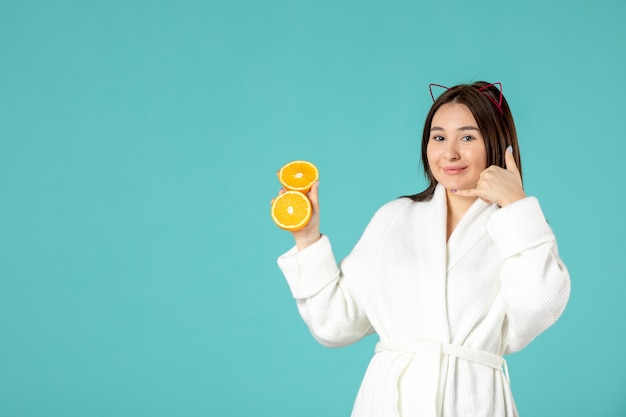 front view young female in bathrobe holding sliced orange on blue background