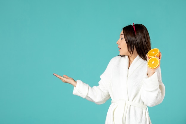 front view young female in bathrobe holding sliced orange on blue background