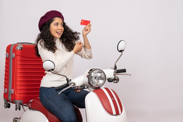 Front view young female on bike holding red bank card on a white background city road vehicle motorcycle speed vacation money color