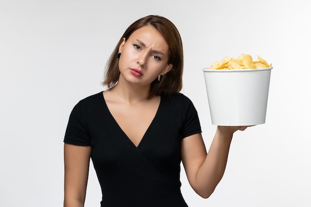 Front view young female in black shirt holding potato chips and posing on light white surface