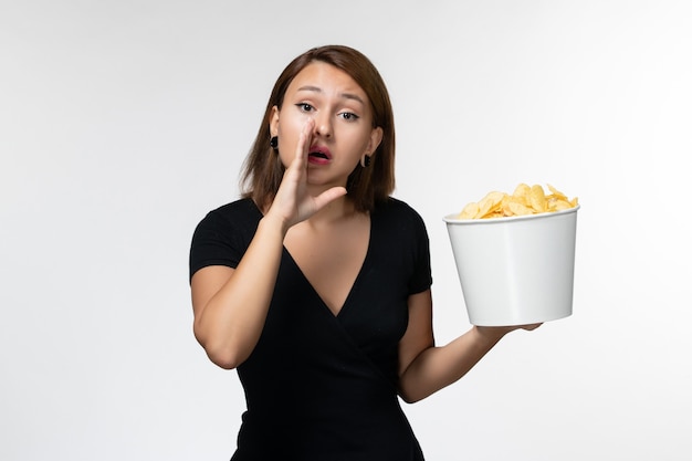 Front view young female in black shirt holding potato chips whispering on white surface