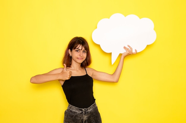 Free photo front view of young female in black shirt holding white sign on light yellow wall