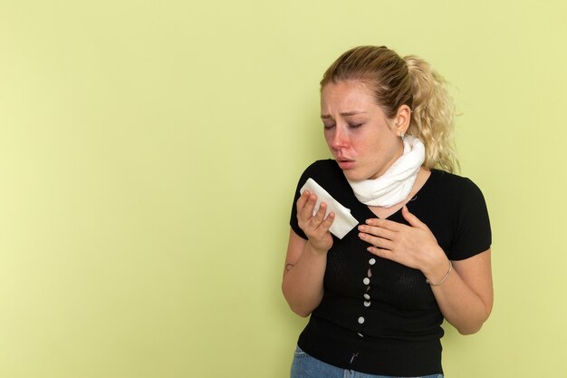 Front view young female in black shirt white towel around her throat feeling very sick and ill on the green wall illness sickness female color health