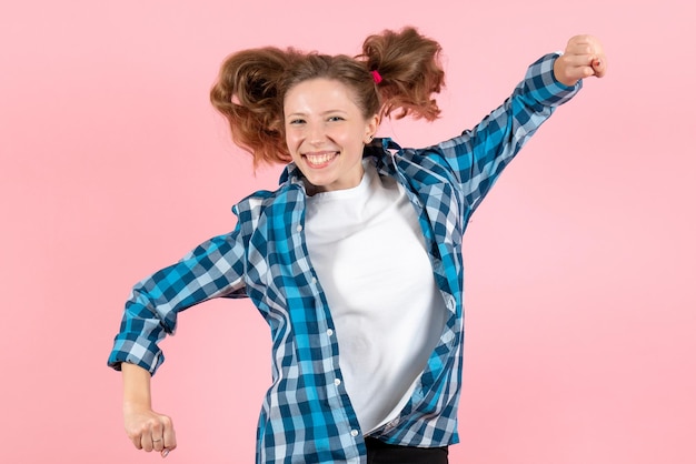 Vista frontale giovane donna in camicia a scacchi blu che salta sul muro rosa donna emozioni modello moda ragazze colore