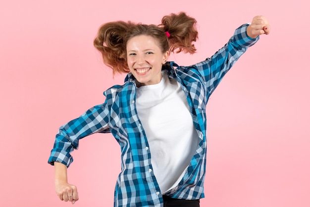 Вид спереди молодая женщина в синей клетчатой рубашке прыгает на розовой стене женщина эмоции модель мода девушки цвет