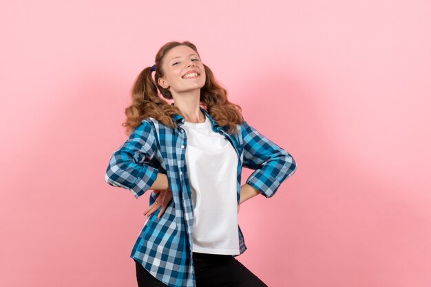 ピンクの背景にポーズをとる青い市松模様のシャツの正面図若い女性女性の感情の女の子のカラーモデルのファッション