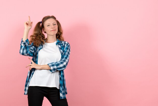 Front view young female in blue checkered shirt posing on the pink background woman kid youth color emotion model