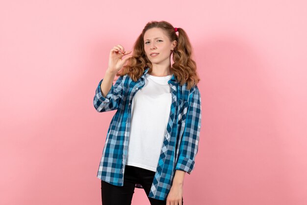 Вид спереди молодая женщина в синей клетчатой рубашке позирует на розовом фоне молодежные эмоции девушка модель мода ребенок