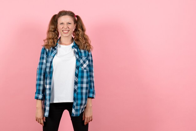 Front view young female in blue checkered shirt posing on pink desk woman emotion girl fashion color model