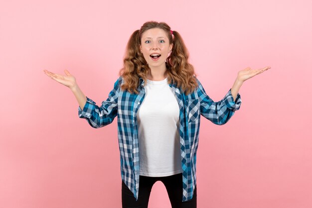 Front view young female in blue checkered shirt posing on pink desk youth emotions girl kid model fashion