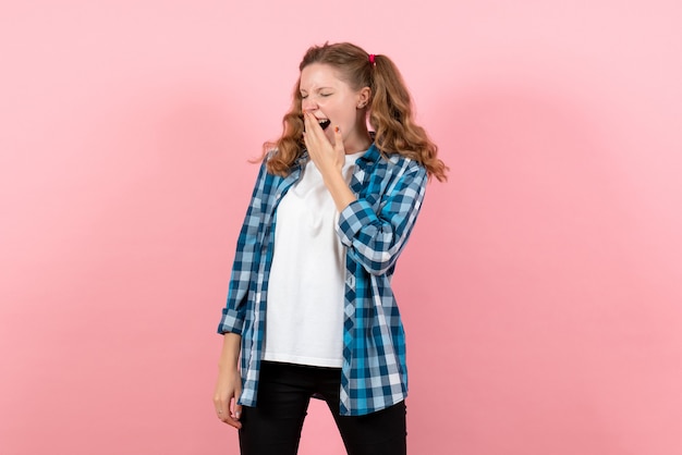 Front view young female in blue checkered shirt yawning on pink background emotion girl fashion model youth kid