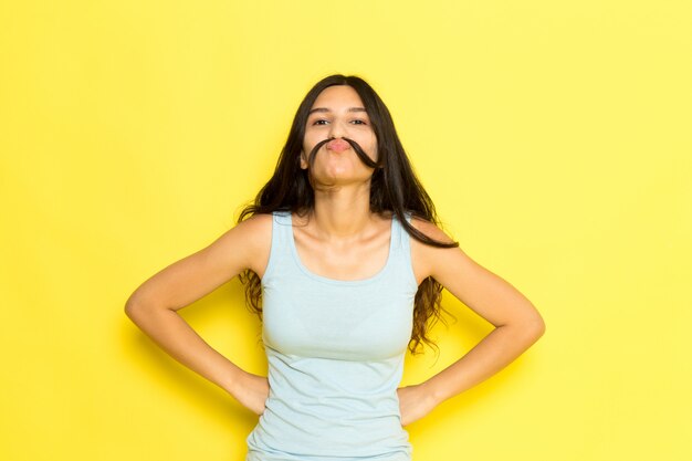A front view young female in blue shirt posing with her hair as a mustache